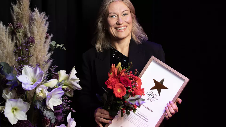 Bild på Malin Andersson som håller i blommor och ett diplom.