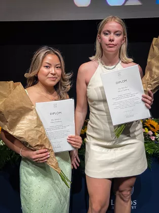 Två finklädda personer som håller ett diplom.